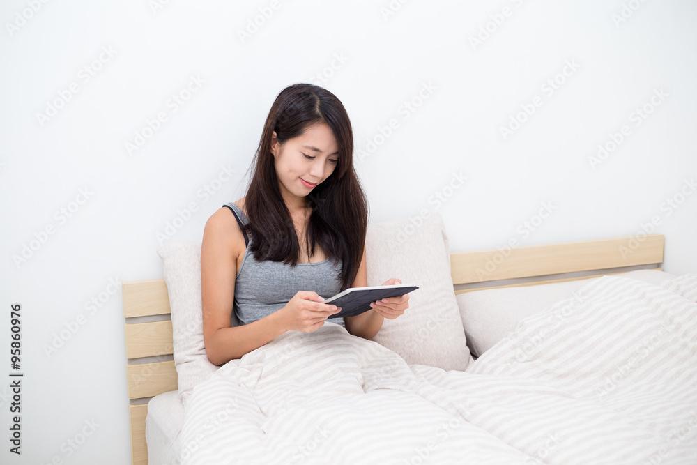 Woman using the tablet and sitting on bed Woman using the tablet and sitting on bed