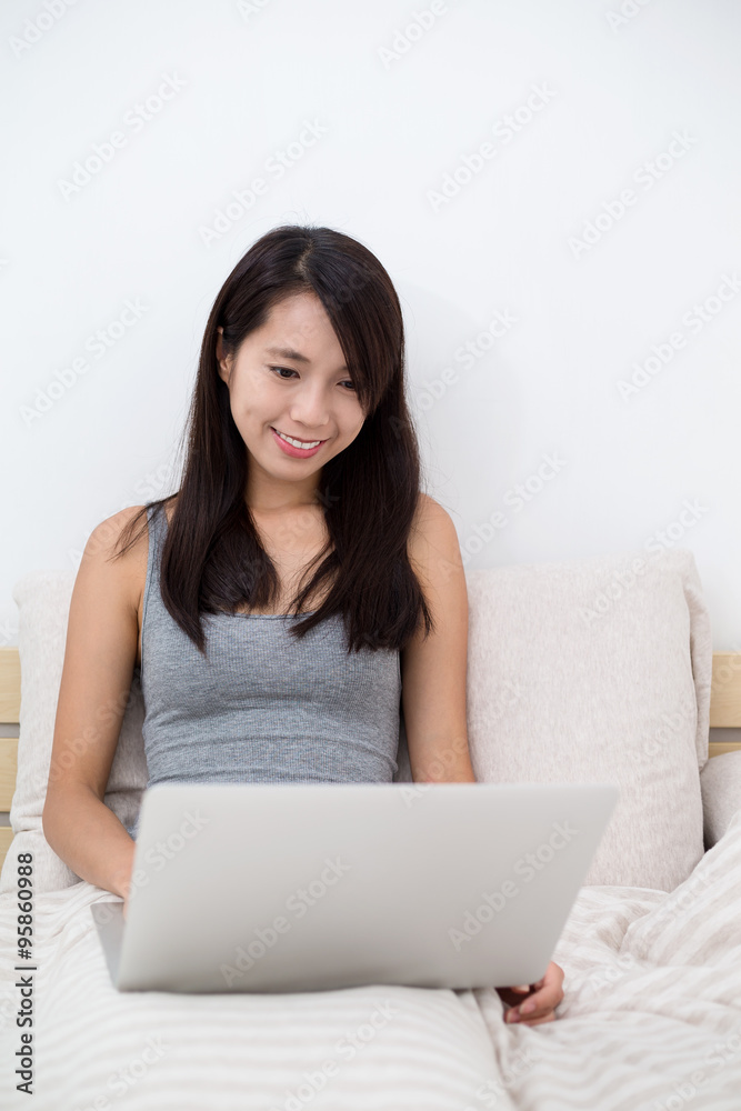 Woman using the notebook computer and sitting on bed Woman using the notebook computer and sitting on bed