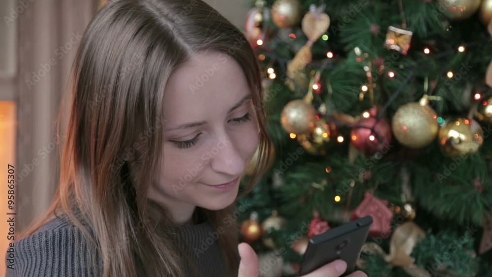 Woman using her mobile phone at christmas at home in the living room Woman using her mobile phone at christmas at home in the living room