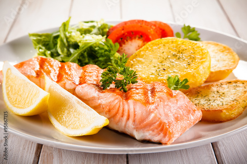 Fried salmon and vegetables on white background