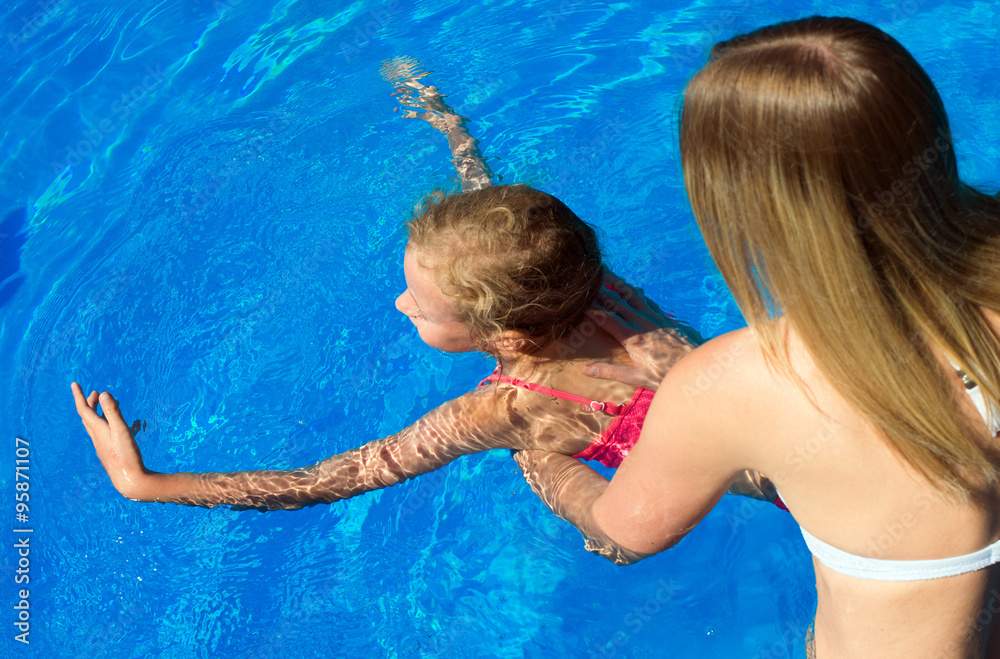 Woman teaching little girl to swim. Place for text.
