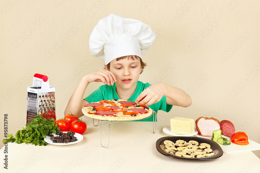 Little funny chef puts the ingredients on the pizza crust Little funny chef puts the ingredients on the pizza crust