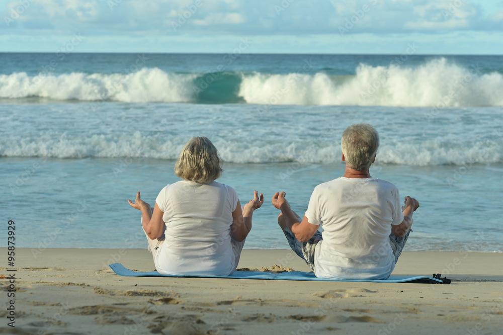 Fototapeta premium elderly couple meditate on beach