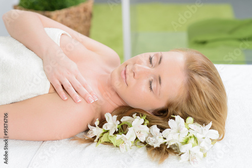 Beautiful woman wrapped in a towel laying in spa with white flow