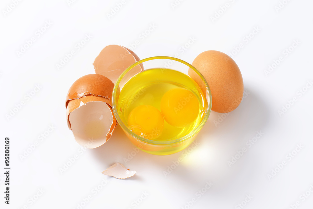 Egg whites and yolks in glass bowl