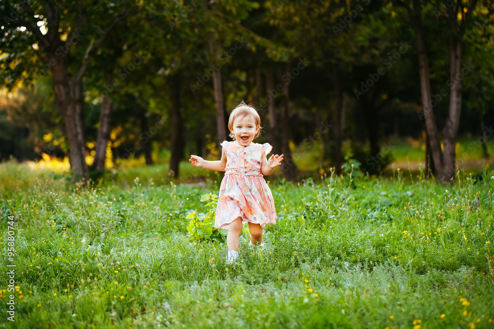 Happy cute little girl running on the grass in the park. Happine Happy cute little girl running on the grass in the park. Happine