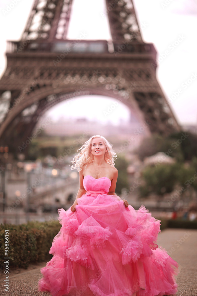 beautiful girl in a pink dress runs on the background Eiffel Tower in Paris
