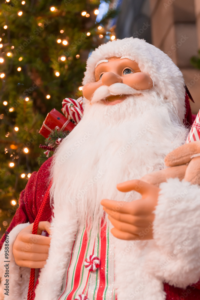 Santa Claus in front of christmas tree.
Twinkle lights in background. Santa Claus in front of christmas tree.
Twinkle lights in background.