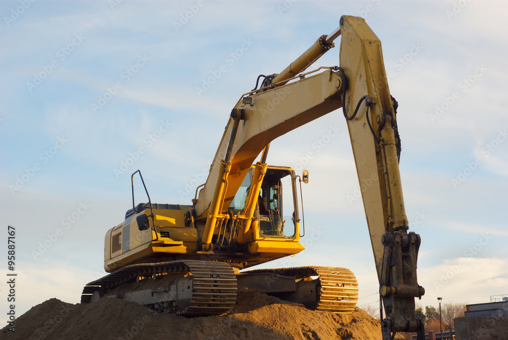 yellow excavator on sandpile in construction site