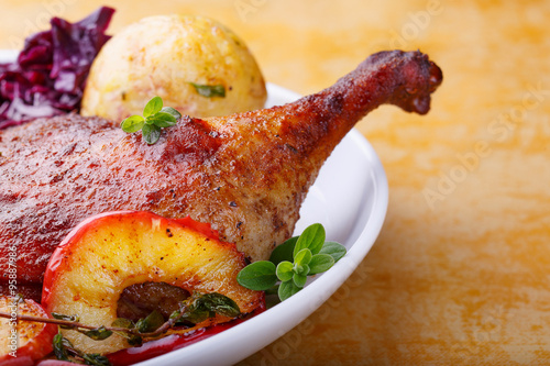 Gebratene Entenkeule mit Rotkohl, Knödel und in Butter gedünsten Apfelscheiben mit MajoranApfelscheiben mit Majoran photo