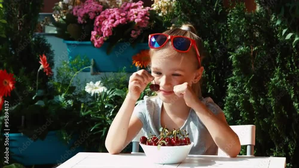 Girl holding a cherry. Child eating berries and admires them Girl holding a cherry. Child eating berries and admires them