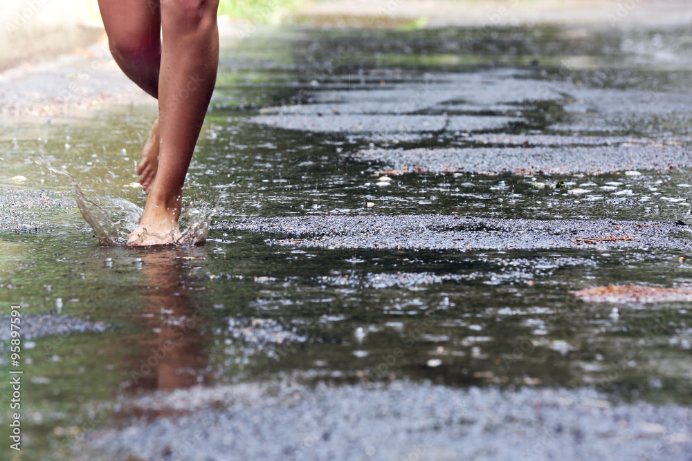 Woman walking barefoot through puddle outdoors Woman walking barefoot through puddle outdoors