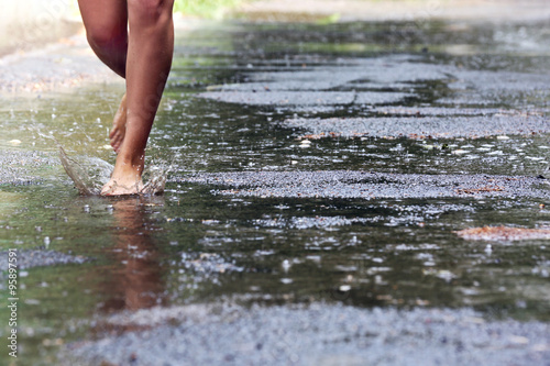 Woman walking barefoot through puddle outdoors © Africa Studio