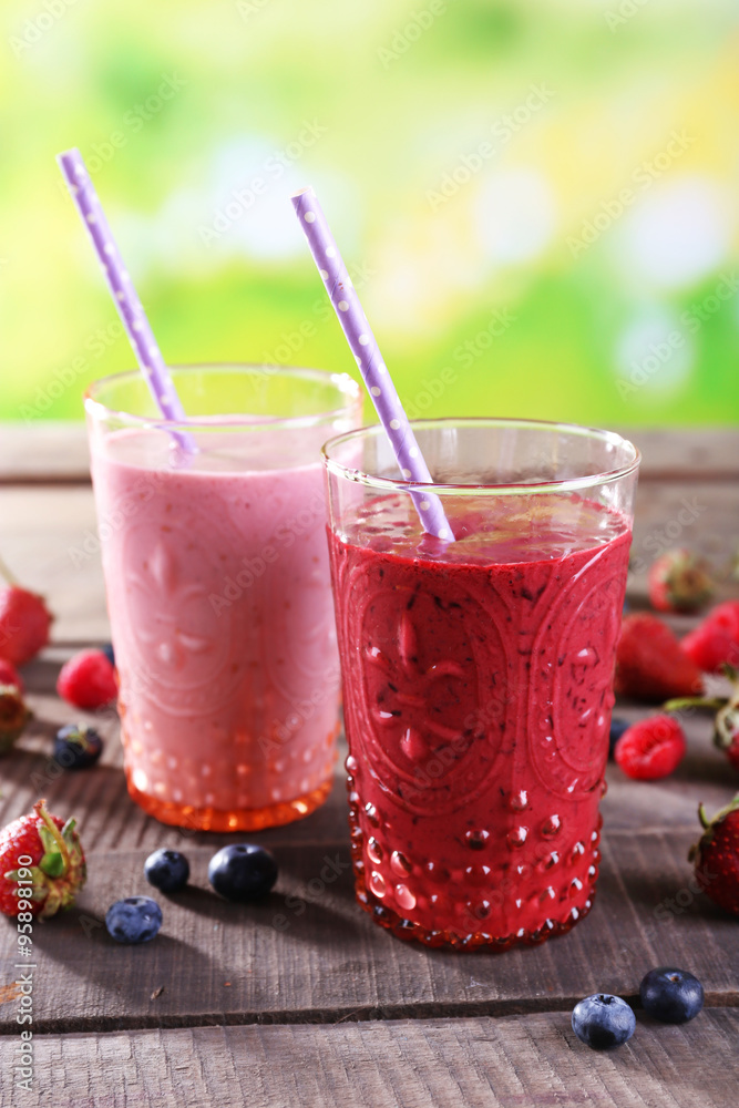 Glasses of berry smoothie on wooden table on blurred background Glasses of berry smoothie on wooden table on blurred background