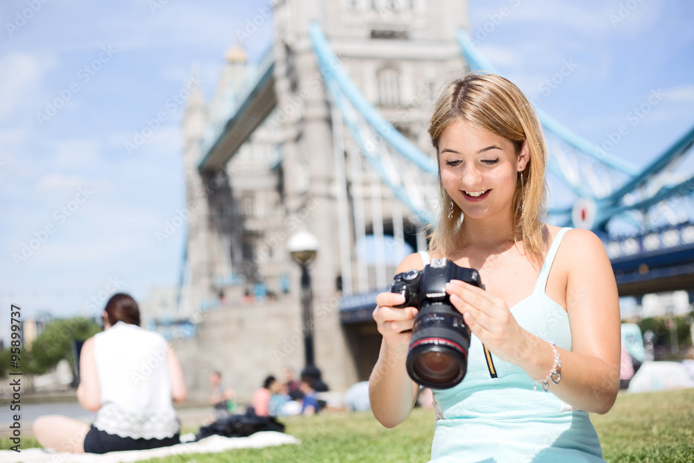young woman looking at photos on her camera by tower bridge young woman looking at photos on her camera by tower bridge