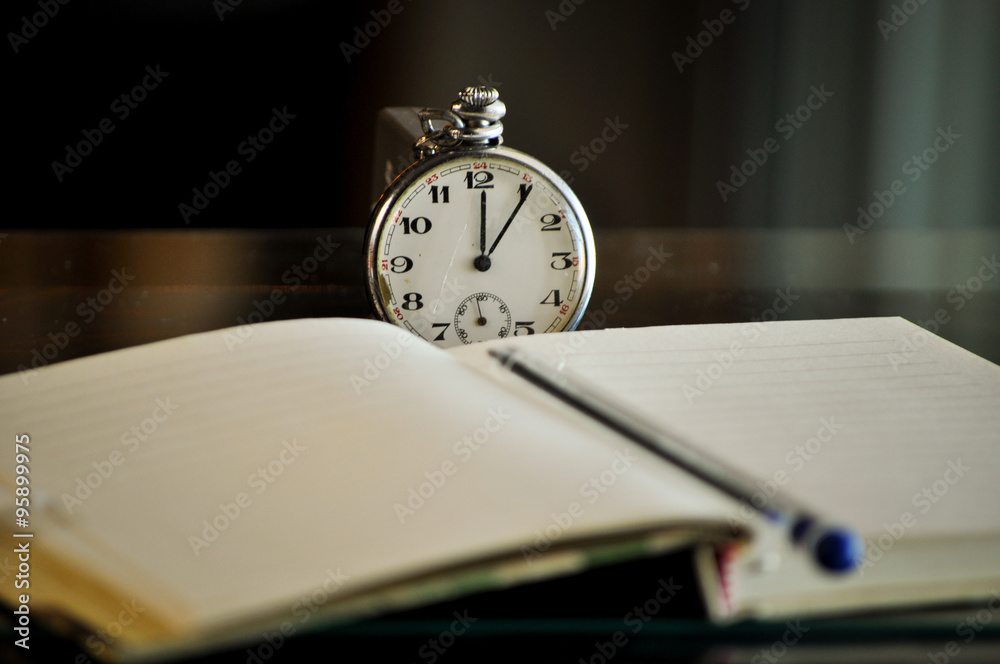 Pocket watch next to notebook. symbols of time Pocket watch next to notebook. symbols of time