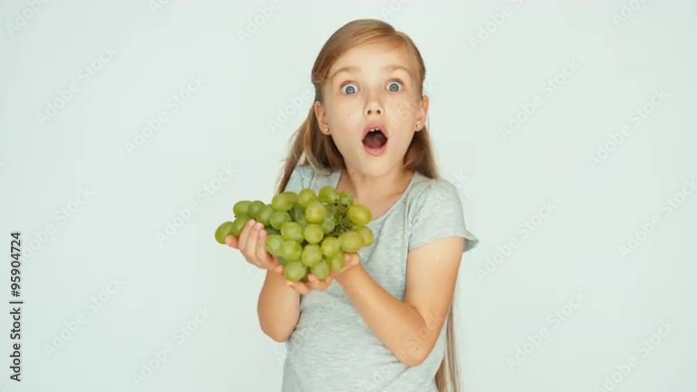 Girl holding grapes in the palm. Child sniffing grapes and laughing. Big eyes Girl holding grapes in the palm. Child sniffing grapes and laughing. Big eyes