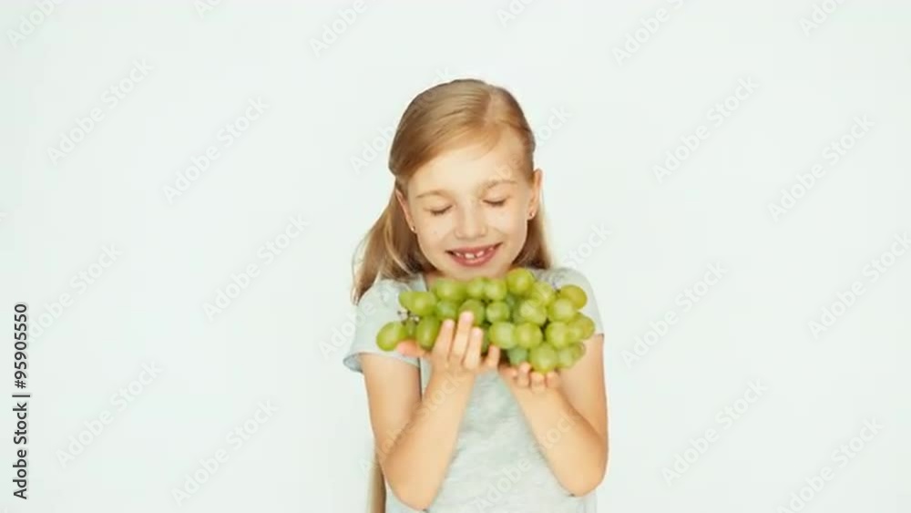 Girl holding grapes in the palm. Child sniffing grapes and smiling Girl holding grapes in the palm. Child sniffing grapes and smiling