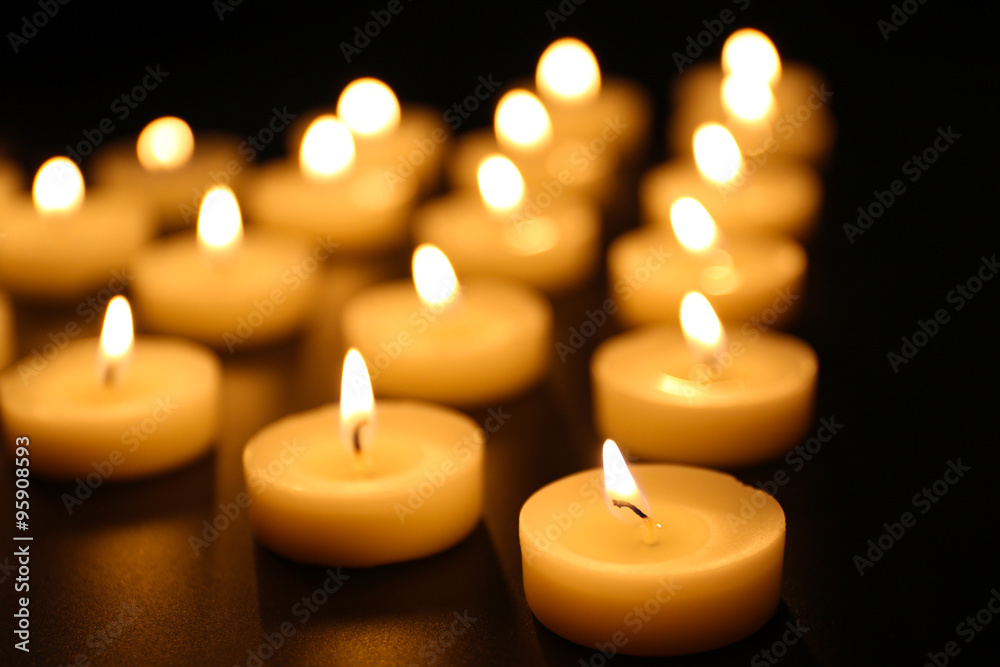 Alight candles in a row on black background, blurred Alight candles in a row on black background, blurred