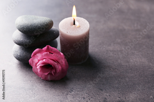 Aroma candle with pebbles and flower on grey background