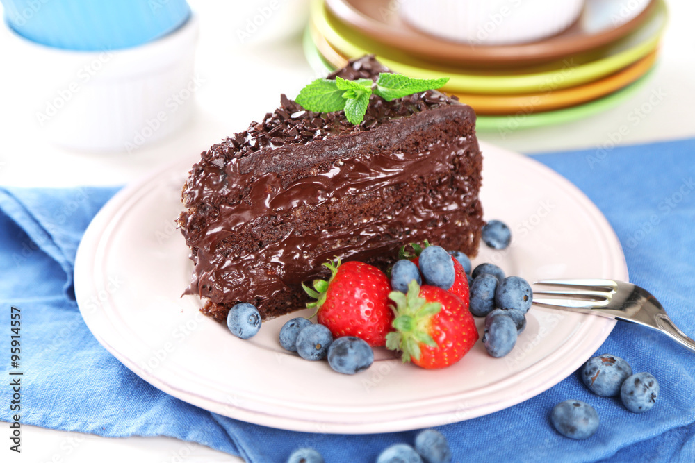 Chocolate cake with chocolate cream and fresh berries on plate, on wooden background Chocolate cake with chocolate cream and fresh berries on plate, on wooden background