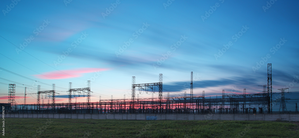 electricity transmission pylon silhouetted against blue sky at d