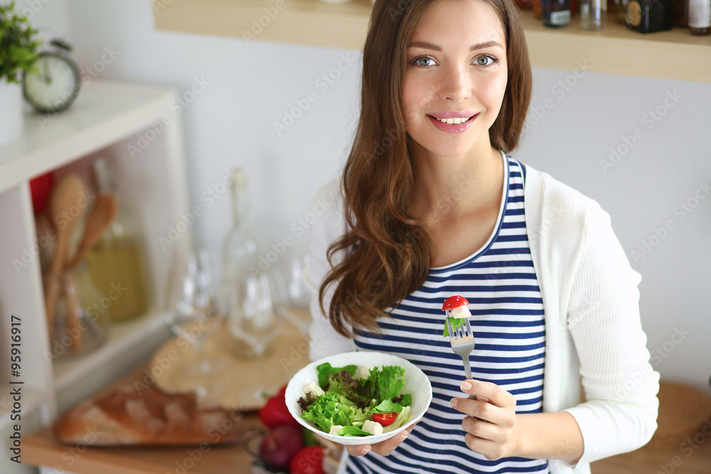 Young woman eating salad and holding a mixed salad Young woman eating salad and holding a mixed salad
