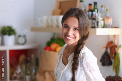 Young woman standing near desk in the kitchen