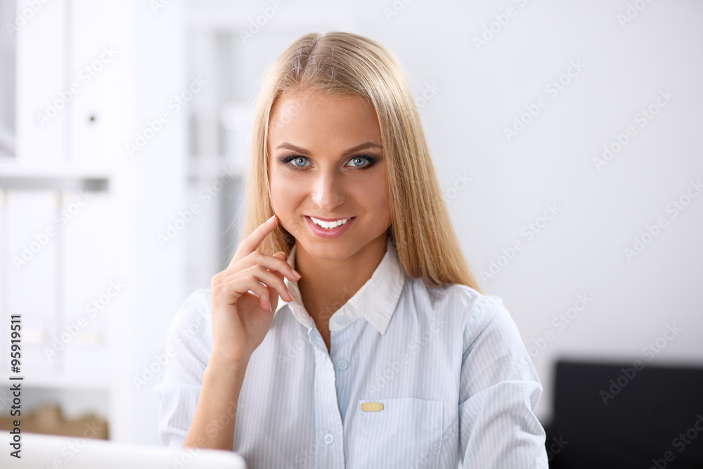 Attractive businesswoman sitting on a desk with laptop in the office Attractive businesswoman sitting on a desk with laptop in the office