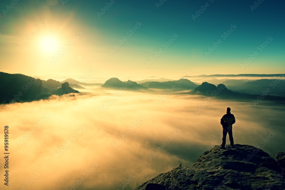 Man stands on peak of sandstone rock in Saxony Switzerland park and watching to Sun. Beautiful miracle of nature