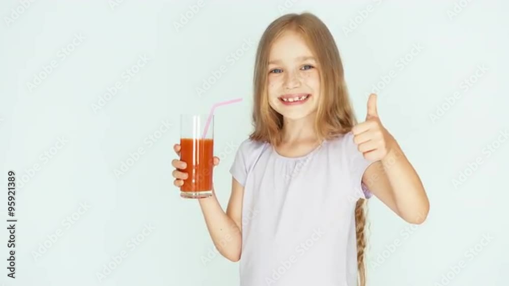 Girl holding glass of red orange mandarin juice. Girl with beautiful blond hair on a white background. Thumb up. Ok Girl holding glass of red orange mandarin juice. Girl with beautiful blond hair on a white background. Thumb up. Ok