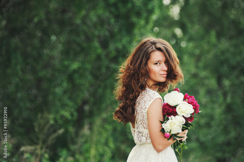 Happy bride with a bouquet of peonies on the background blurred tree. Happy bride with a bouquet of peonies on the background blurred tree.
