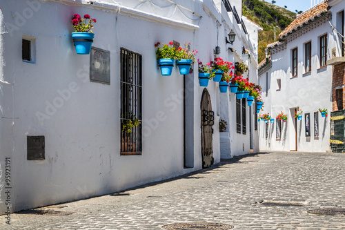 Cuadro en lienzo Picturesque street of Mijas with flower pots in facades. Andalus