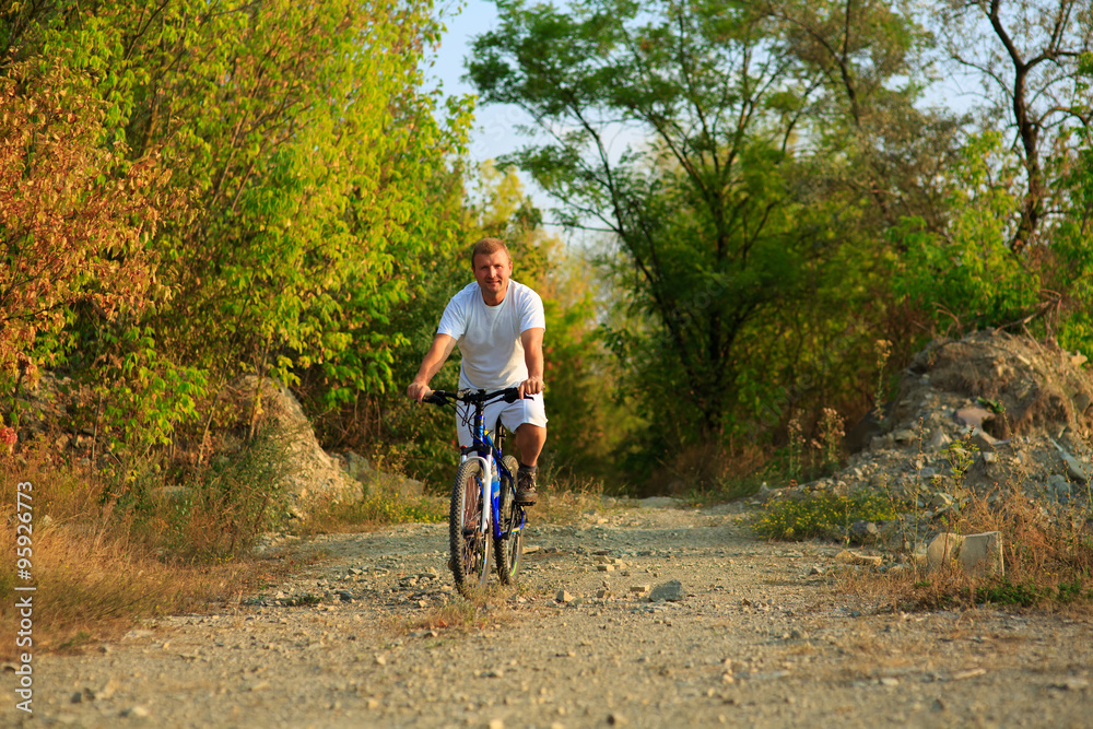 Man with bicycle riding country road