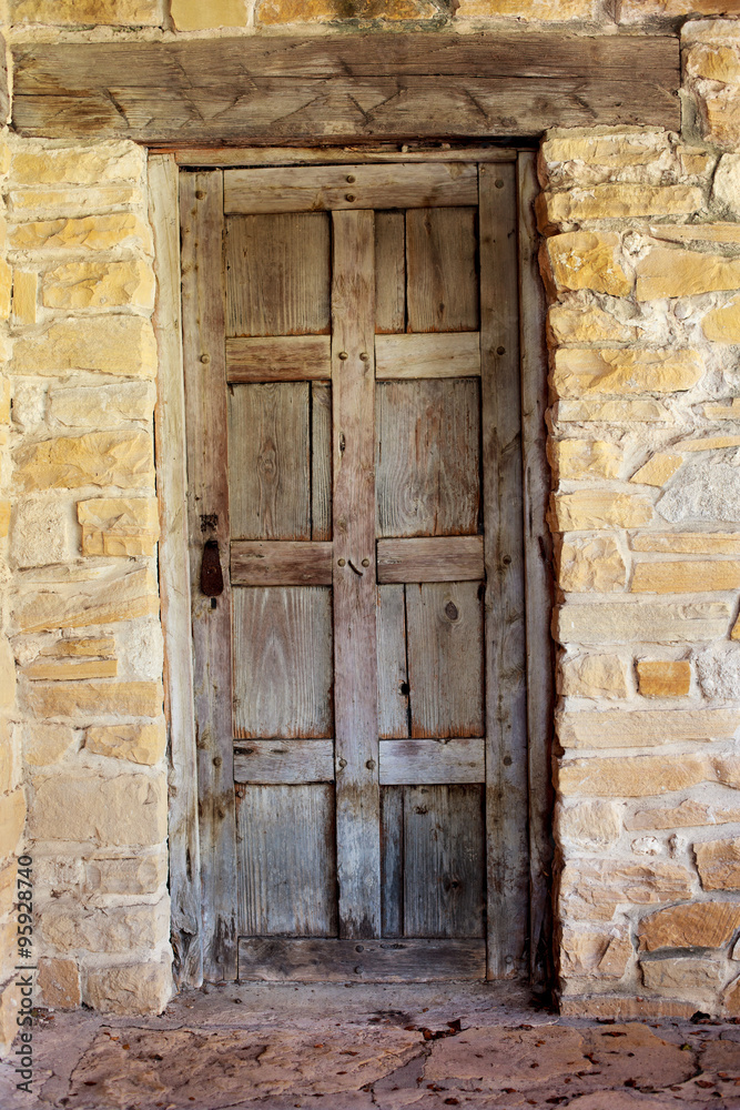 Wooden Door against Worn Stone Wall / An Interesting View of a Rustic Wooden Door against Worn Stone Wall