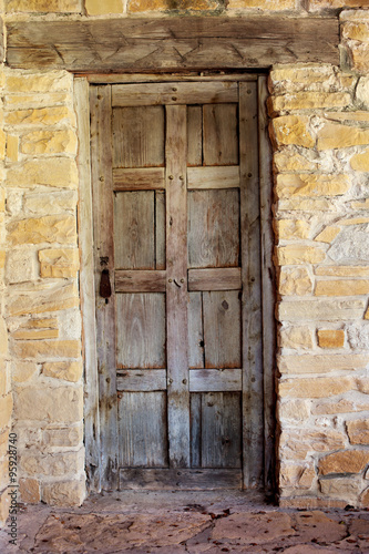 Wooden Door against Worn Stone Wall / An Interesting View of a Rustic Wooden Door against Worn Stone Wall