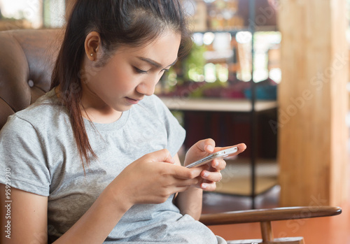 young woman holding a smart phone on the background of cafe, soft and selective focus