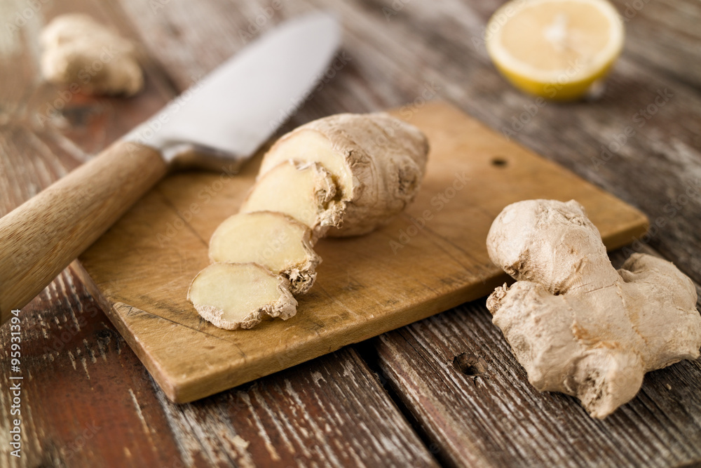 Sliced ginger and knife on wood cutting board rustic setting Sliced ginger and knife on wood cutting board rustic setting