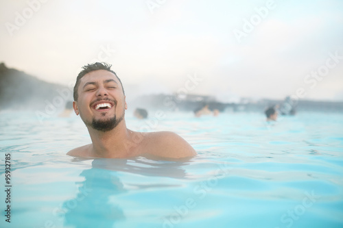 Laughing hispanic young man relaxing in a pool in Iceland. Happy young man in water. © kegfire