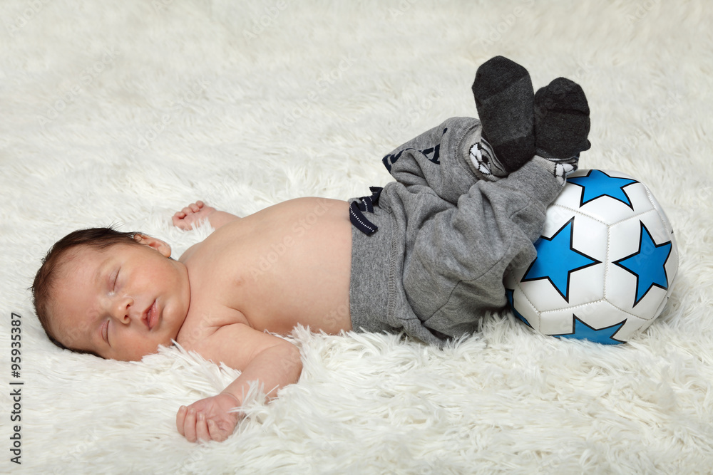 Śpiące niemowlę z piłką, noworodek. - obrazy, fototapety, plakaty 