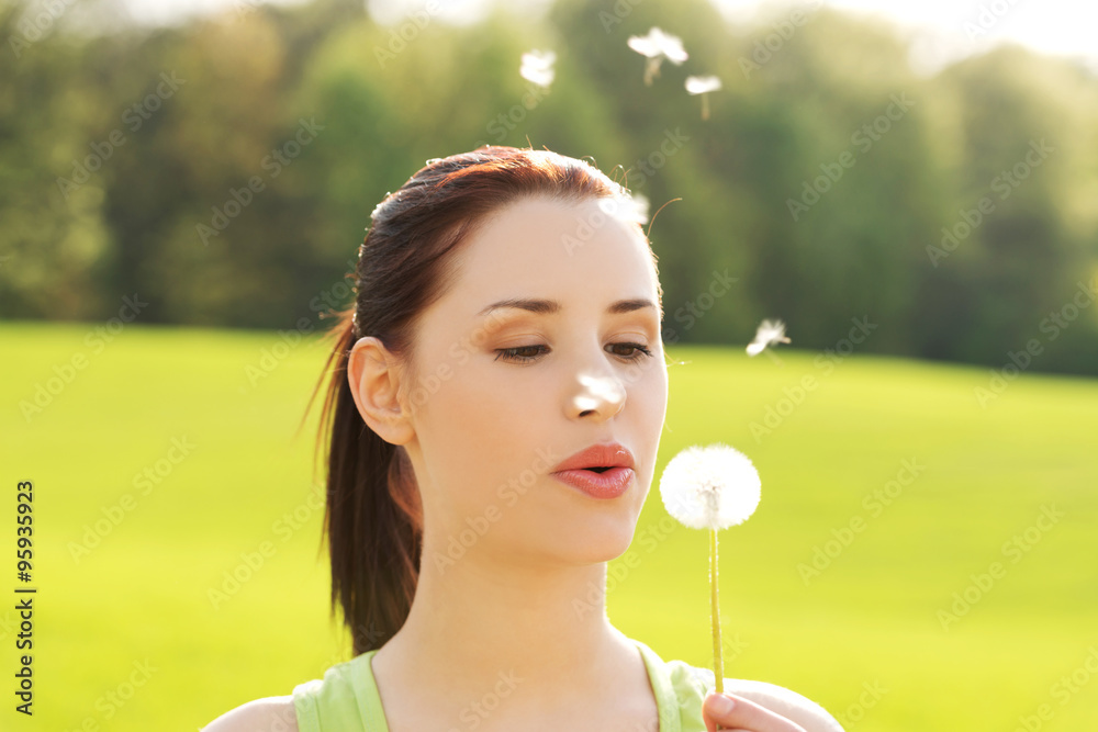 Woman blowing on a dandelion