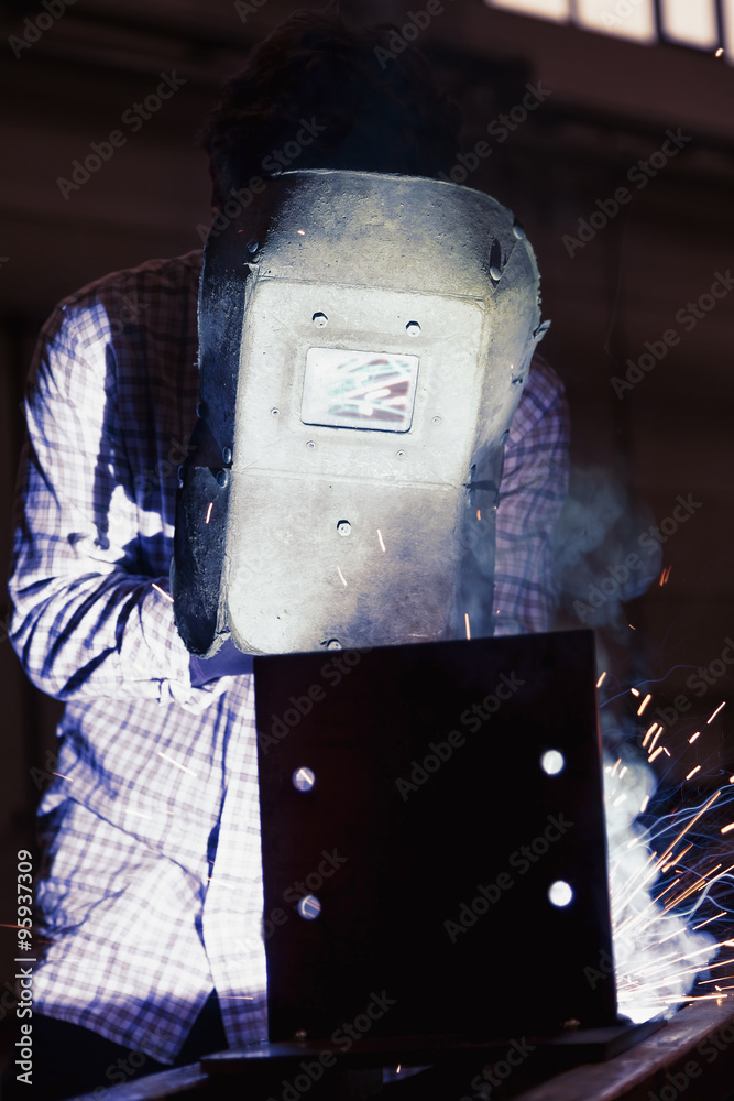 young worker while welding steel
