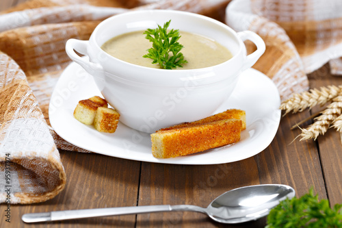 A cup of vegetable soup with parsley and fried bread on a dining