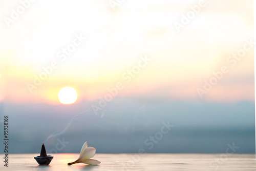 Smoke incense cones with plumeria flower on sunset