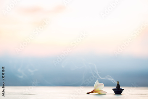 Smoke incense cones with plumeria flower on sunset photo