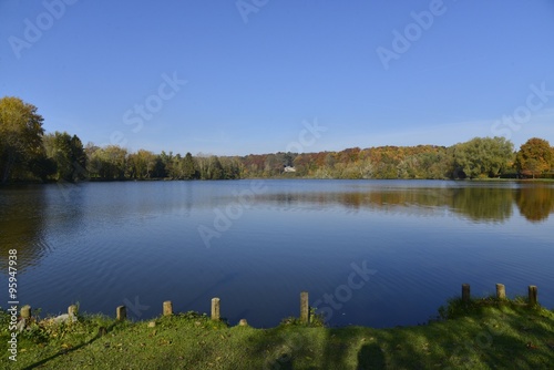 Le grand étang de la Hulpe en automne sous un ciel bleu 