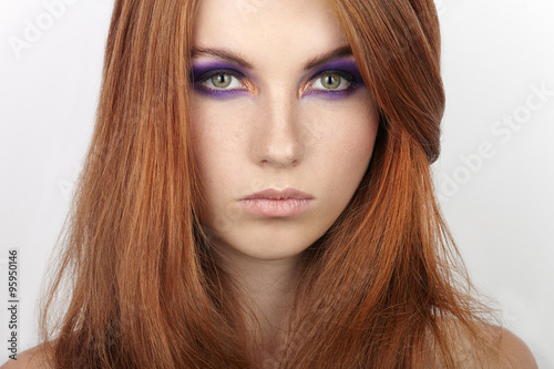 Closeup portrait of young beautiful redhead woman with gorgeous hair and violet eyes makeup