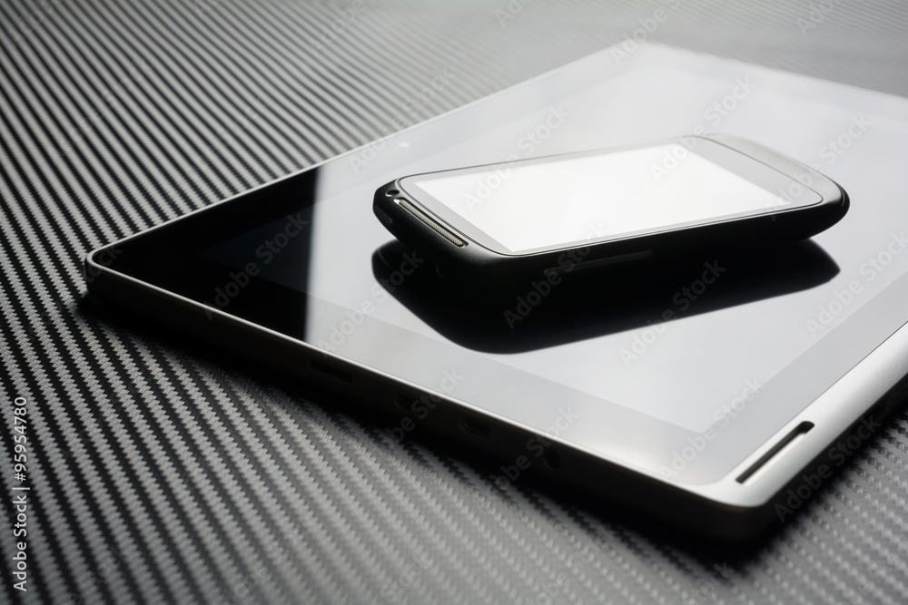 Blank Smartphone With Reflection Lying On Business Tablet With Reflection On Carbon Background