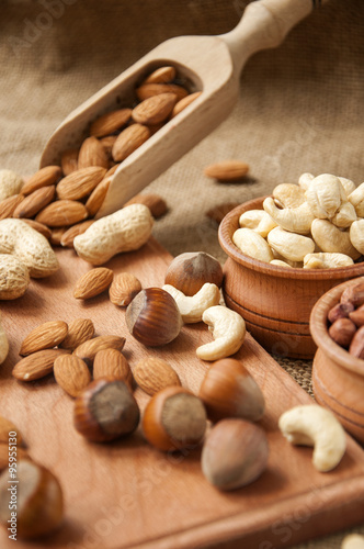 Almonds, cashew and hazelnuts in wooden bowls on wooden and burlap background