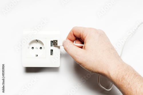 Plug in. A man inserts the usb plug into the usb port of power s